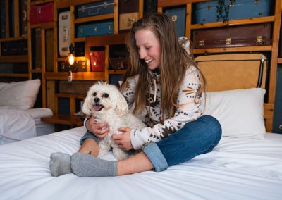 A lady is sitting on a bed at the Dog Friendly Hotel in Squamish Crash Hotel